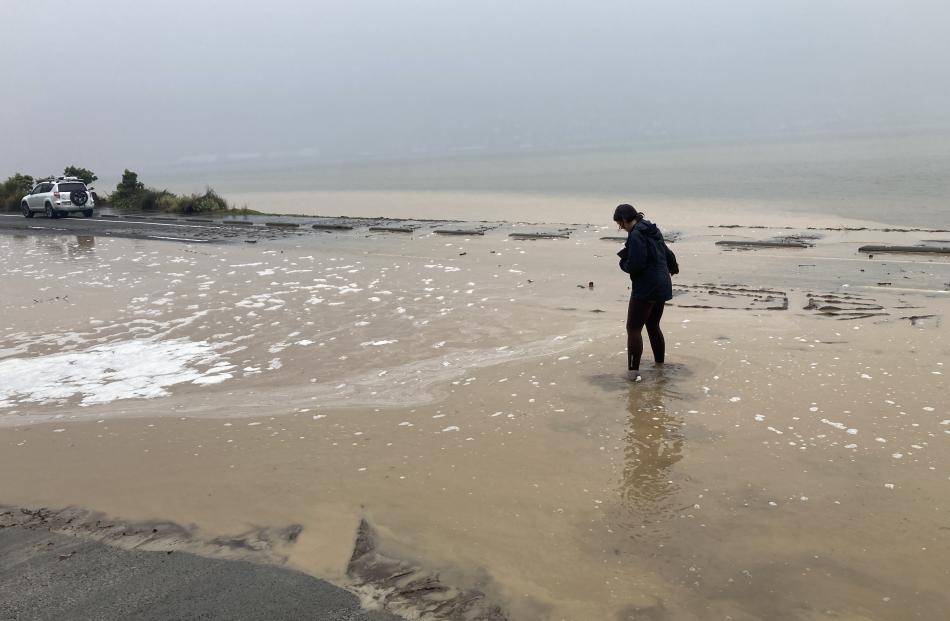 A pedestrian attempts to navigate the flooded Portobello Road. Photo: Stephen Jaquiery