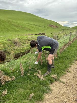 Handy Landys member Hamish Goatley holds a fence post on a flood damaged fence in South Otago.
