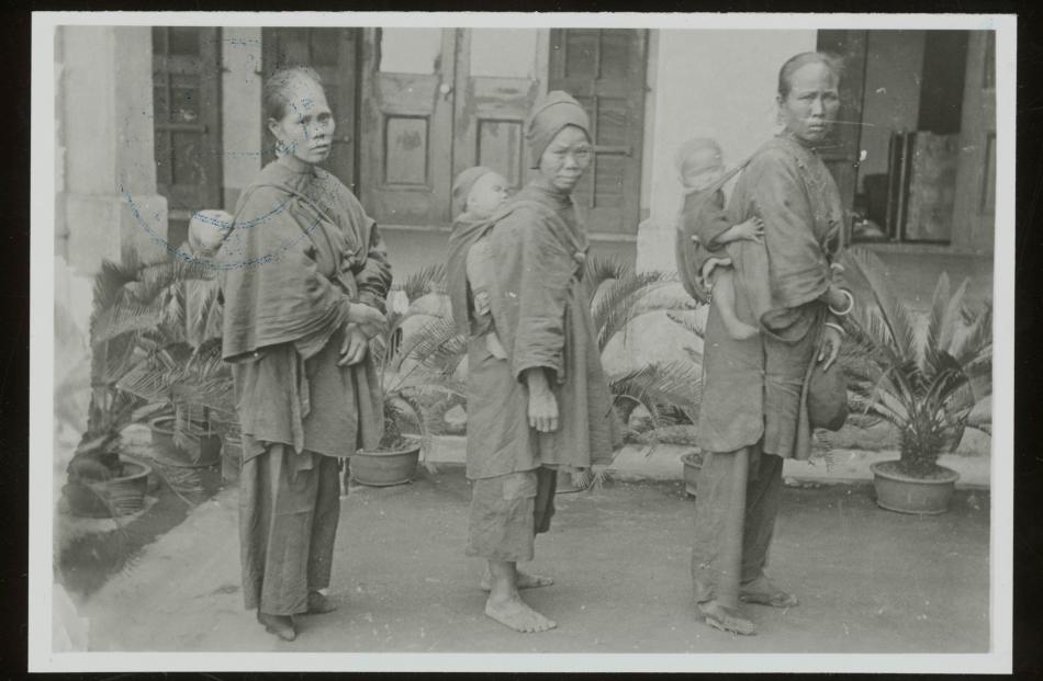 In this photo from 1905, three Chinese women carry babies on their backs. The woman on the left...
