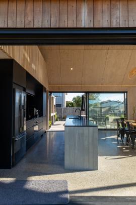Sliding doors either side of the kitchen lead outside; the island is of board-formed concrete...