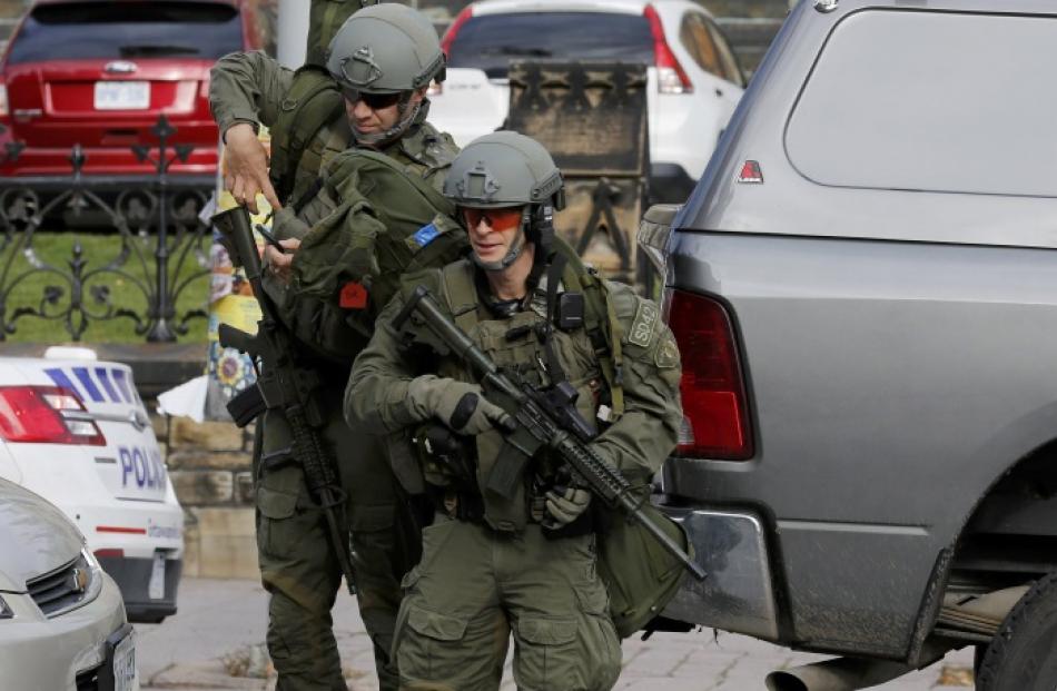 Armed RCMP officers approach Parliament Hilll following a shooting incident in Ottawa. Photo by...