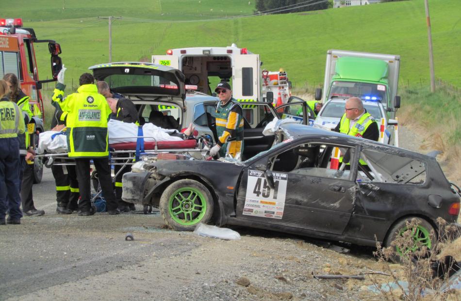 Treated . . . Paramedics (left) treat the driver beside his crashed car where it came to rest...