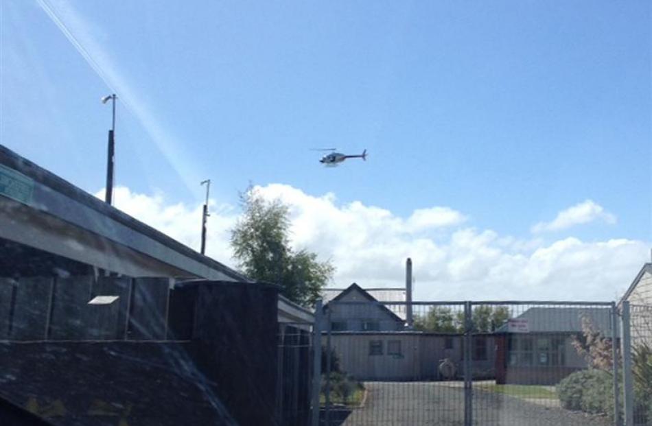 A helicopter flies over Otatara School after an armed robbery in Otatara yesterday. Photo by Kym...