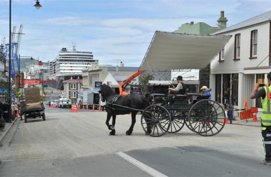 A horse-drawn wagon turns on George St with the cruise ship Oosterdam in the background.