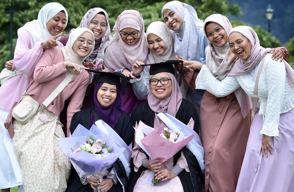 Surrounded by a crowd of their friends after their graduation from the University of Otago are...
