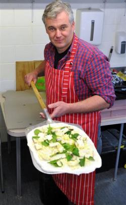 Mamma Mia Pizza Takeaway owner Michal Rozenberg ladles a pizza in the new Roslyn pizzeria in...