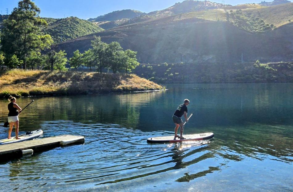 Elise and Matt Saill, of Cromwell, take to their paddle boards on the calm waters of Lake Dunstan...