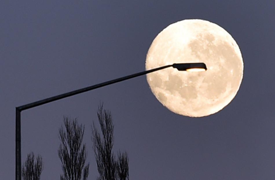 The moon assists a street lamp illuminating the Caversham bypass at Lookout Point on a frosty...