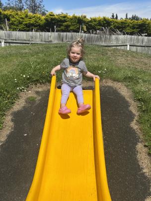 Slip-sliding ... Lucy Moore, 22 months, is set to zoom down a slide at the playground in Lambert...