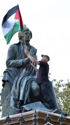 Palestine supporter David Bennett, of Dunedin, places a Palestinian flag in the hands of the...