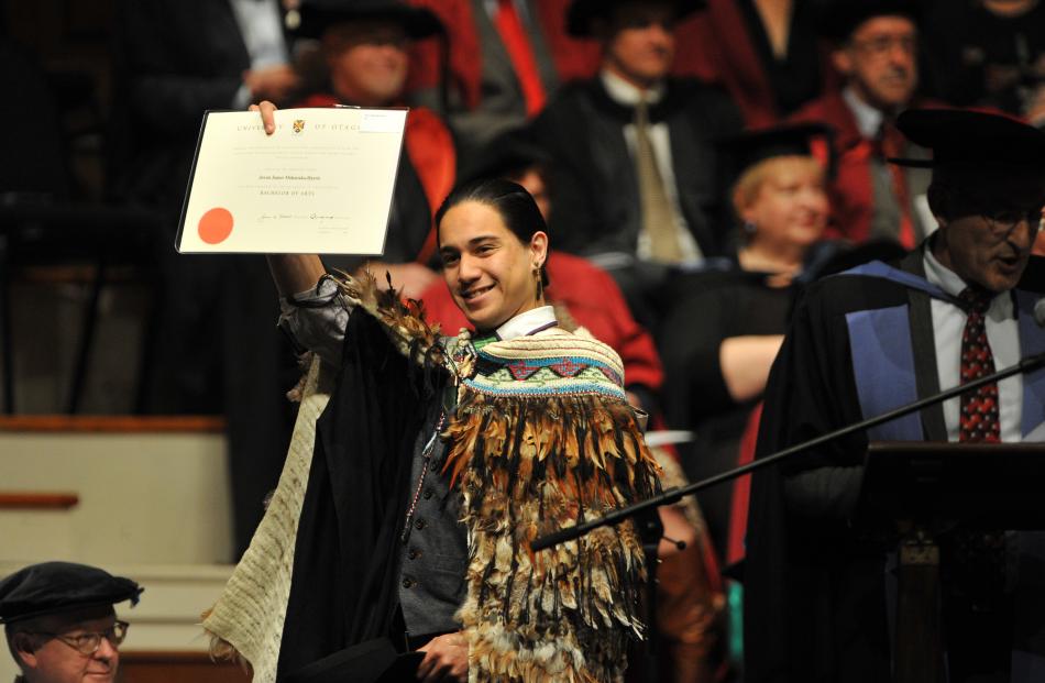 Jovan Mokaraka-Harris holds aloft his bachelor of arts degree certificate during the ceremony.