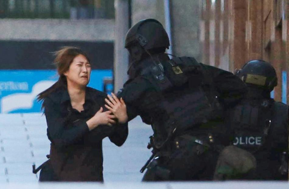 A hostage runs towards a police officer outside the cafe. REUTERS/Jason Reed
