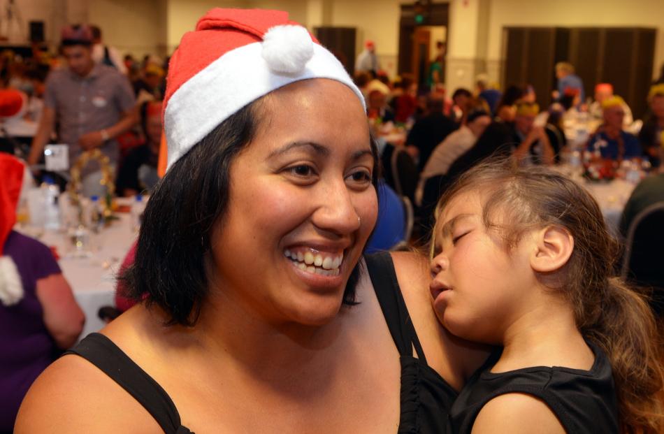 Volunteer Gemma Tuhega holds son Phoenix (2) as she helps out.