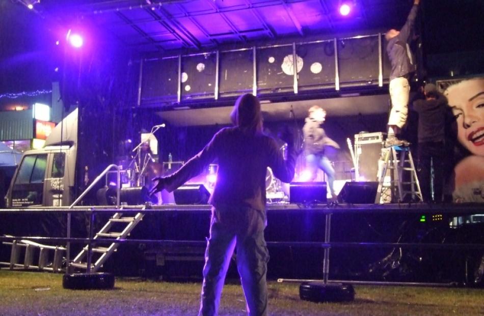 A lone man keeps dancing despite a downpour about 10pm temporarily silencing the live...