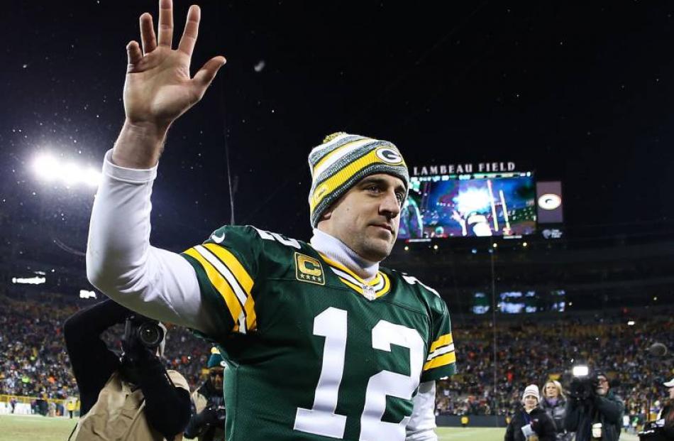 Green Bay Packers quarterback Aaron Rodgers waves to fans as he walks off the field after a win...