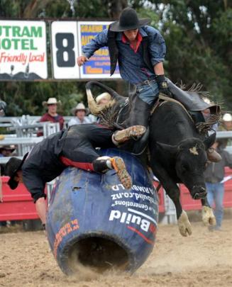 Cowboy Kylie Waru navigates a barrel and bull fighter Mark Tweedie in the second-division bull ride.