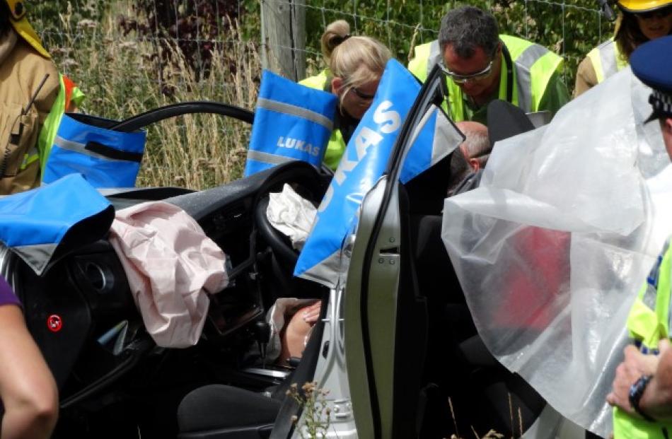 Fire volunteers and St John staff work to extract the driver of a rental car involved in the crash.