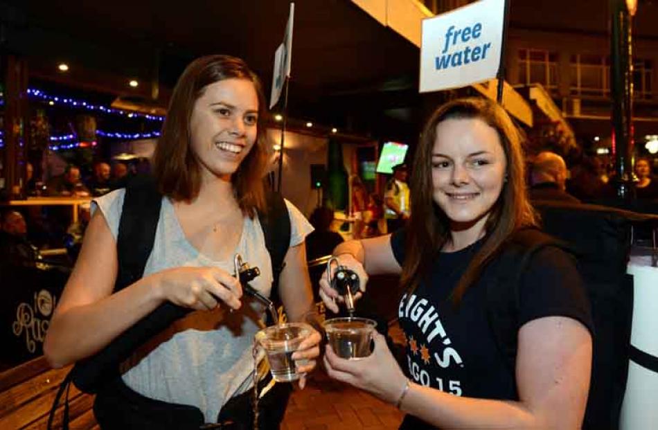 Kendra Forshaw (19, left) and Georgia Williams (21)  provide free water for patrons lining up at...