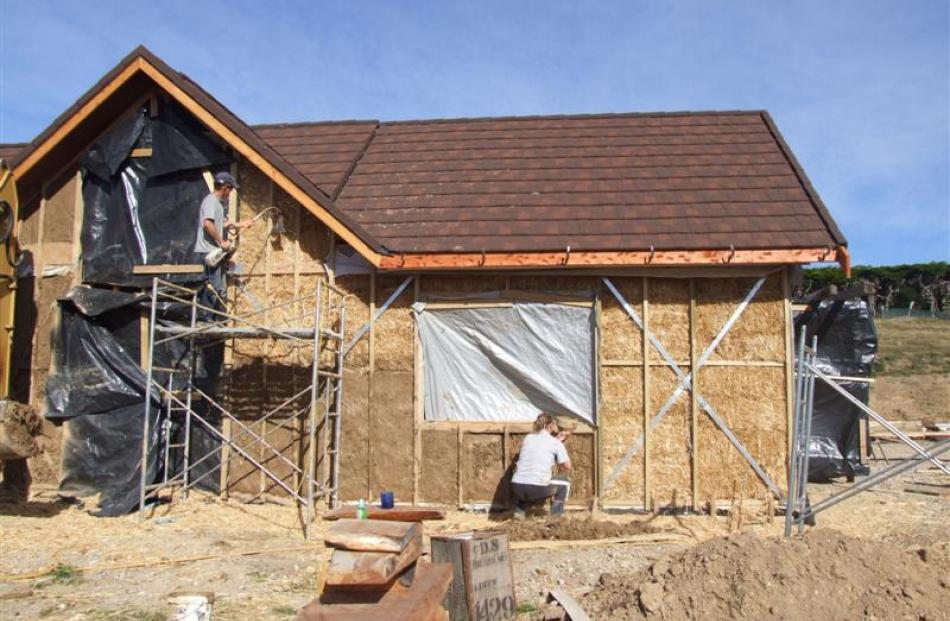 Once the framing and roof were up, the straw bale walls went in and old carpet was fixed around...