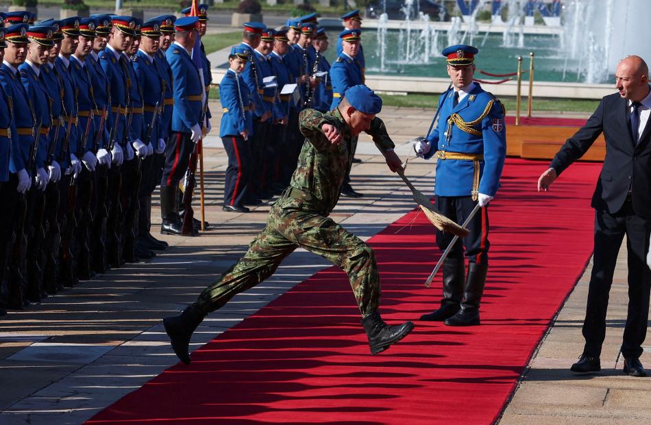 A soldier holding a broom jumps over the red carpet ahead of the welcoming ceremony for the...