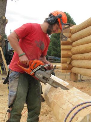Matteo Mignola, of Switzerland, shapes logs as part of the construction process.
