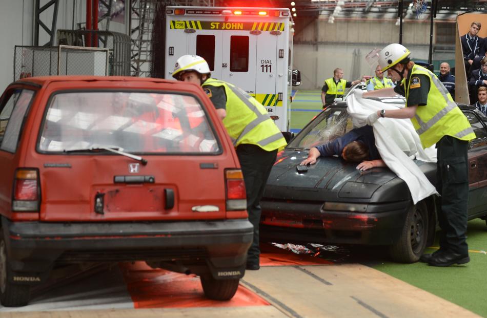 Emergency services staff cover the body - played by an actor - thrown out of a crashed vehicle.