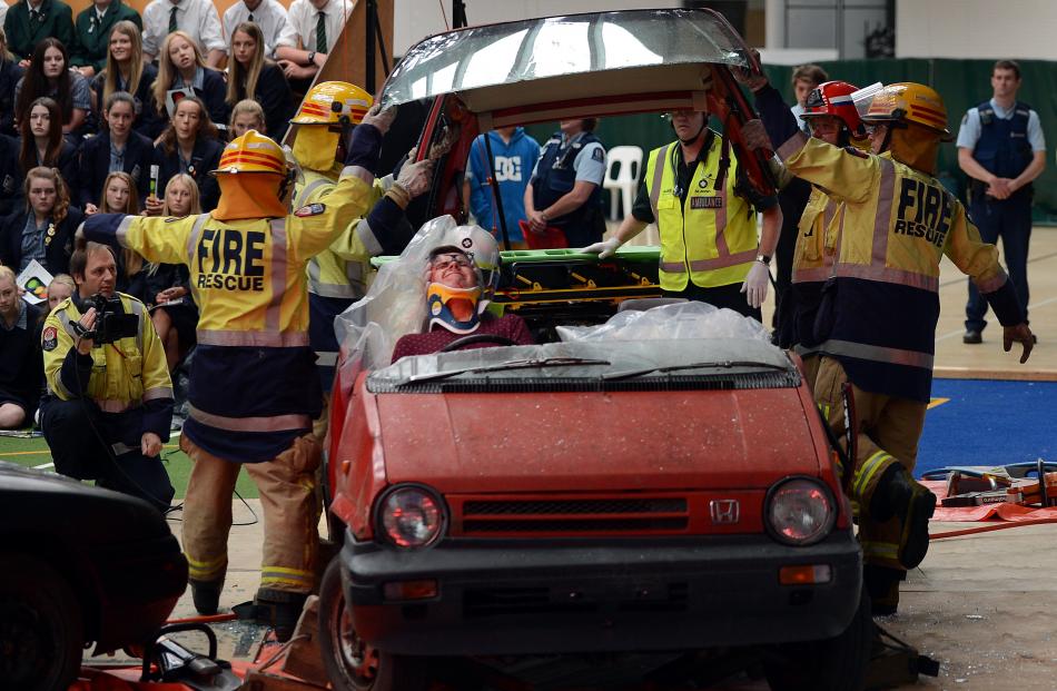 Firefighters remove the roof from a car as actor James Beard (16) plays its seriously injured...