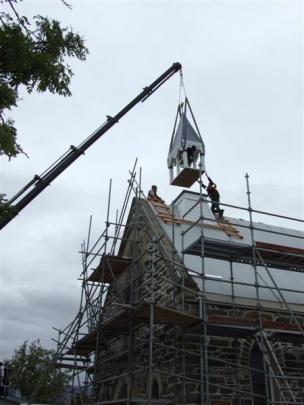 Anthony Robertson, the owner of Lifestyle Construction, guides the bell tower back on to its...