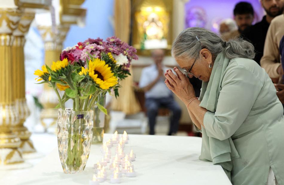 A woman prays during a vigil at the Vishwa Hindu Mandir, in memory of those who lost their lives...