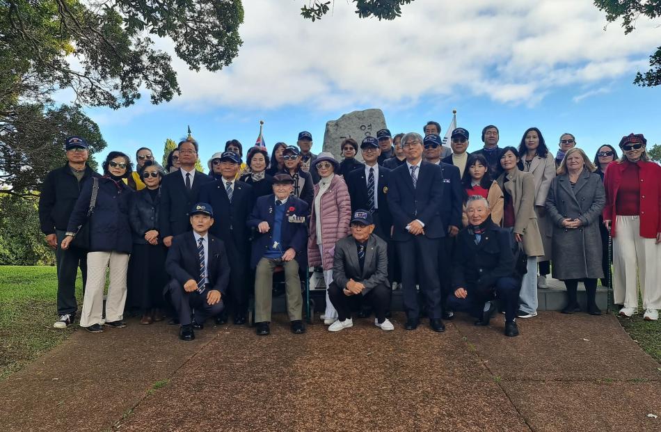 Korean community members and officials gather for a commemorative photo following the Korean War...