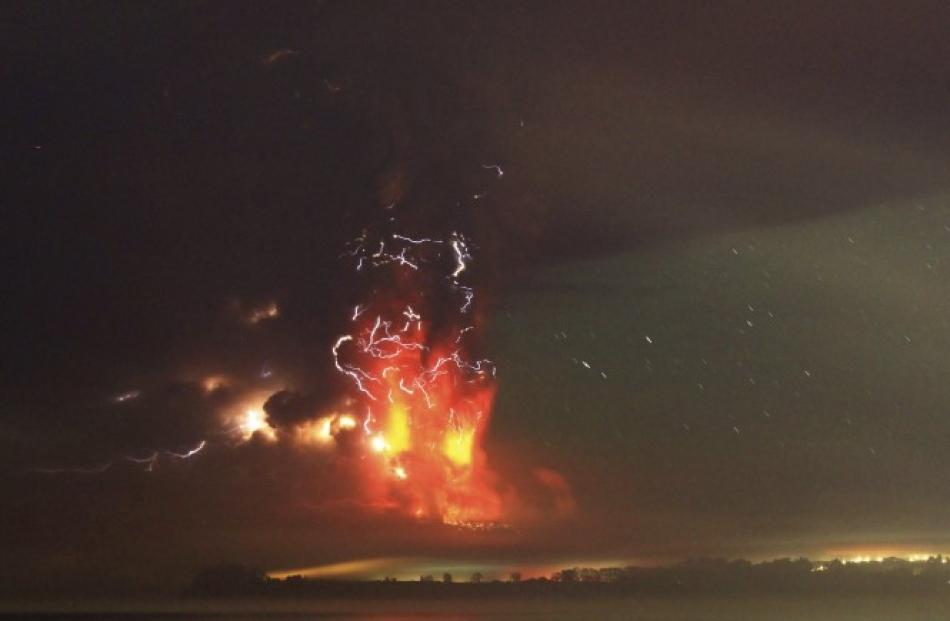 Lightning flashes as smoke and lava spew from the volcano, as seen from the shores of Lake...