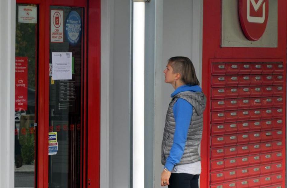 New Zealand Post customer Elisa Humitsch, of Wanaka, reads a notice  explaining the office is...