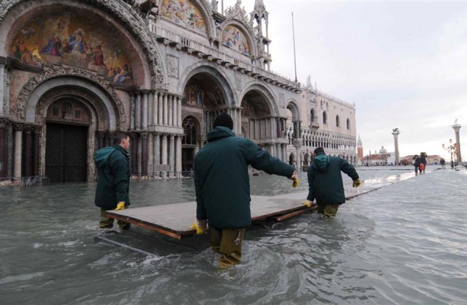 Workers remove the boards usually used to create walkways over the high water as the water level...