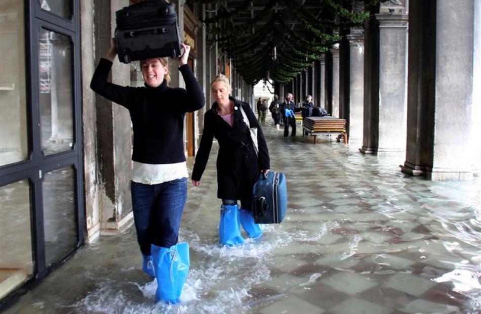 Tourists carry their luggage as they make their way through high water in Venice. Photo Luigi...