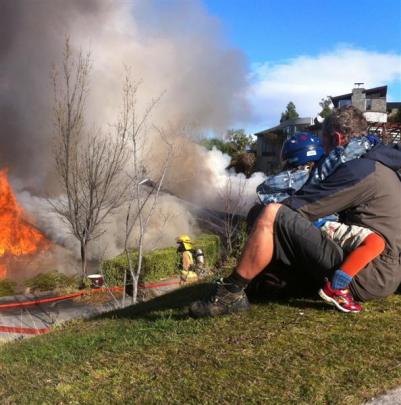 A Queenstown man, clutching his son, watches his house burn. Photos by David Williams.