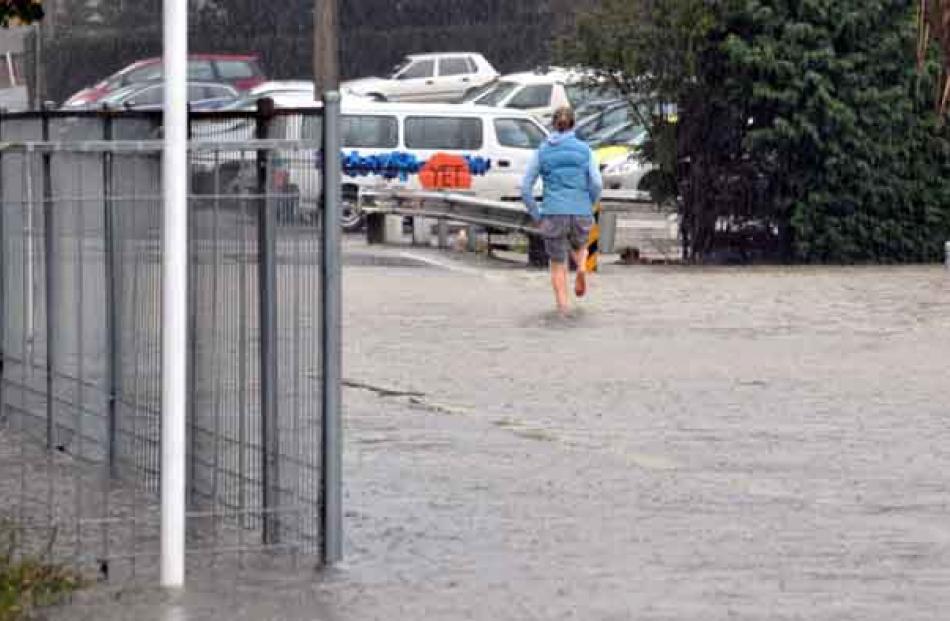 A woman runs through flooding towards East Taieri School.