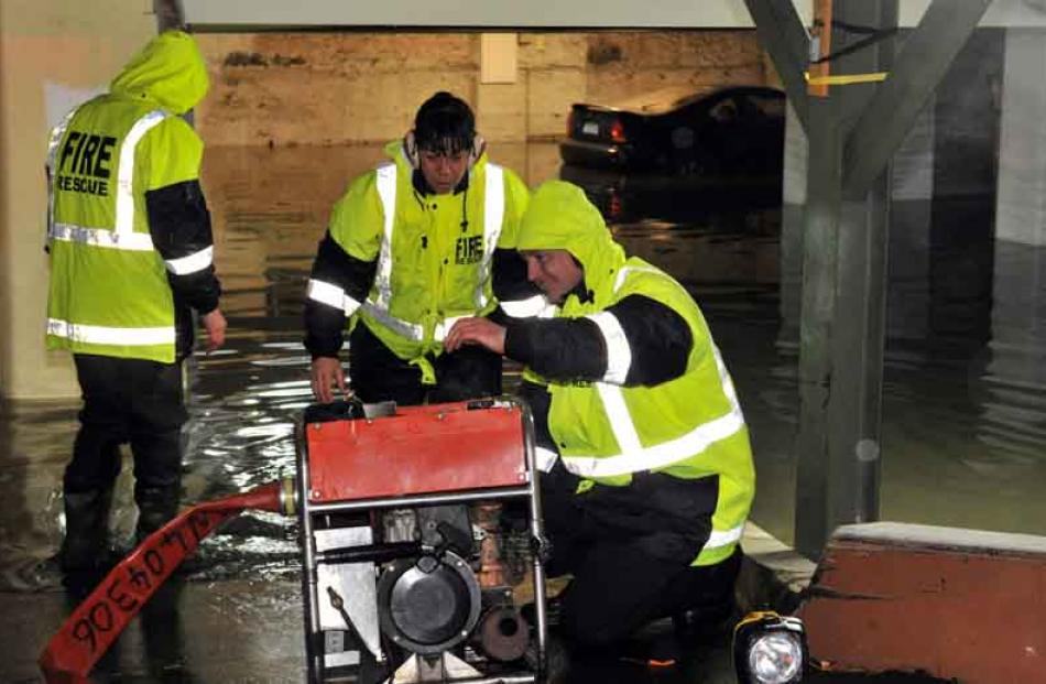 Firefighters set up a pump in a flooded basement, Crawford St.