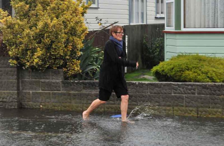Pauline Osborne runs barefooted through the flood waters in Grove St, St Kilda.