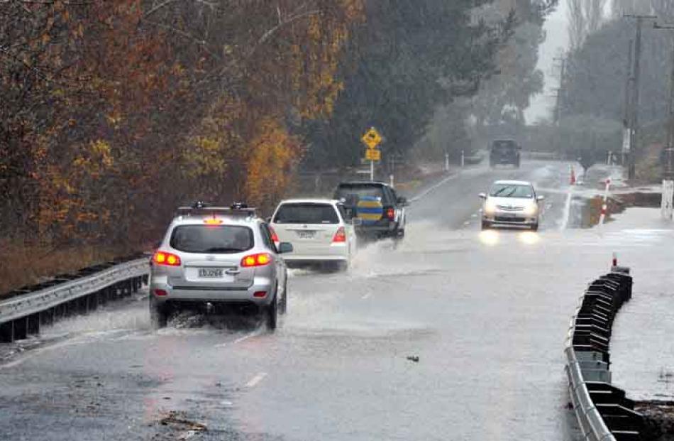 Cars negotiate flooding at the bottom of Three Mile Hill.