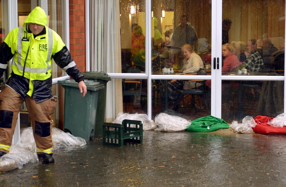 Residents at Fulton home have lunch while a firefighter checks sand bags outside the dining room...