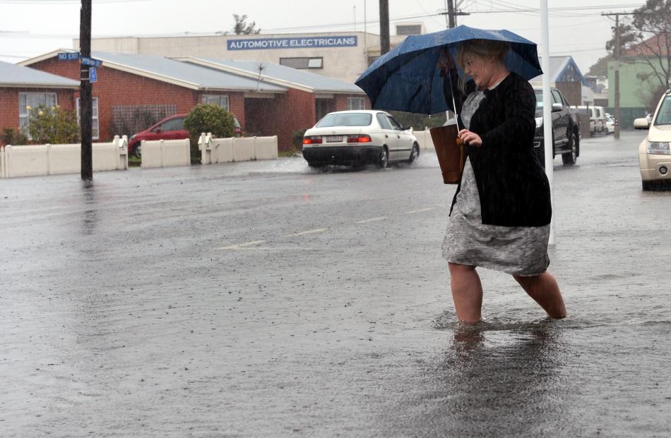 Westpac worker Rebecca Ryan wades home along McBride St about noon after water threatened to...