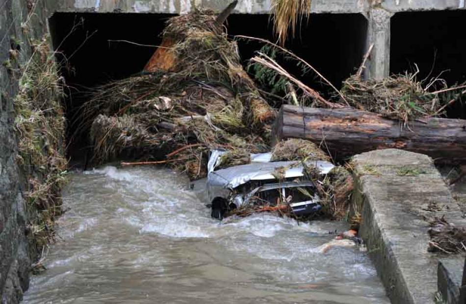 A semi-submerged car lies against debri in the Kaikorai Stream, Green Island.