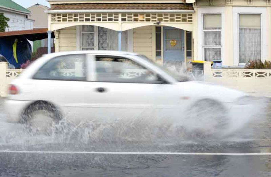 A car speeds through the water in Macandrew Road.