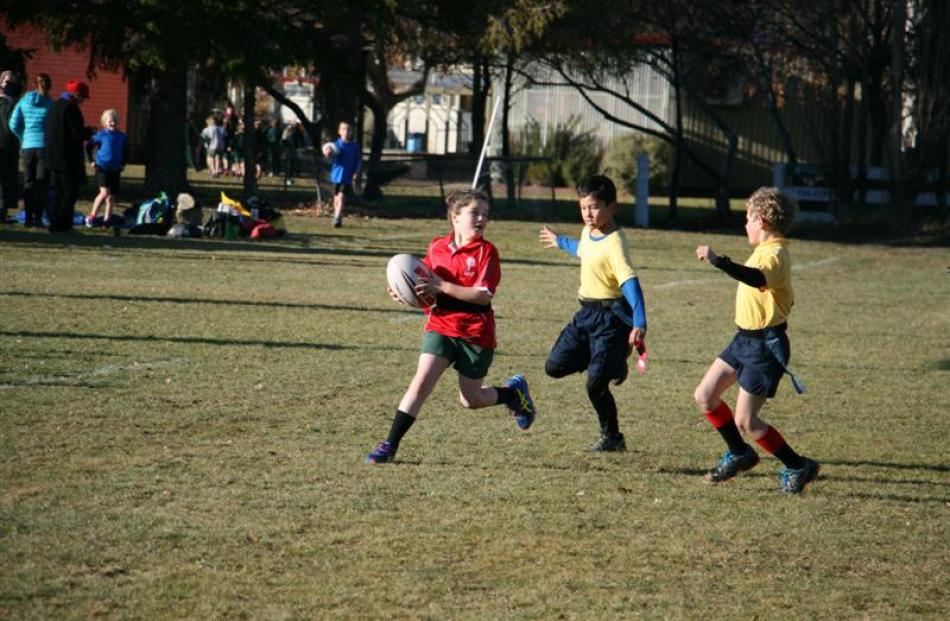 Year 3-4 St Johns Black player Ella Gibson (9, left) is chased by Clyde Red players Tane Morgan ...