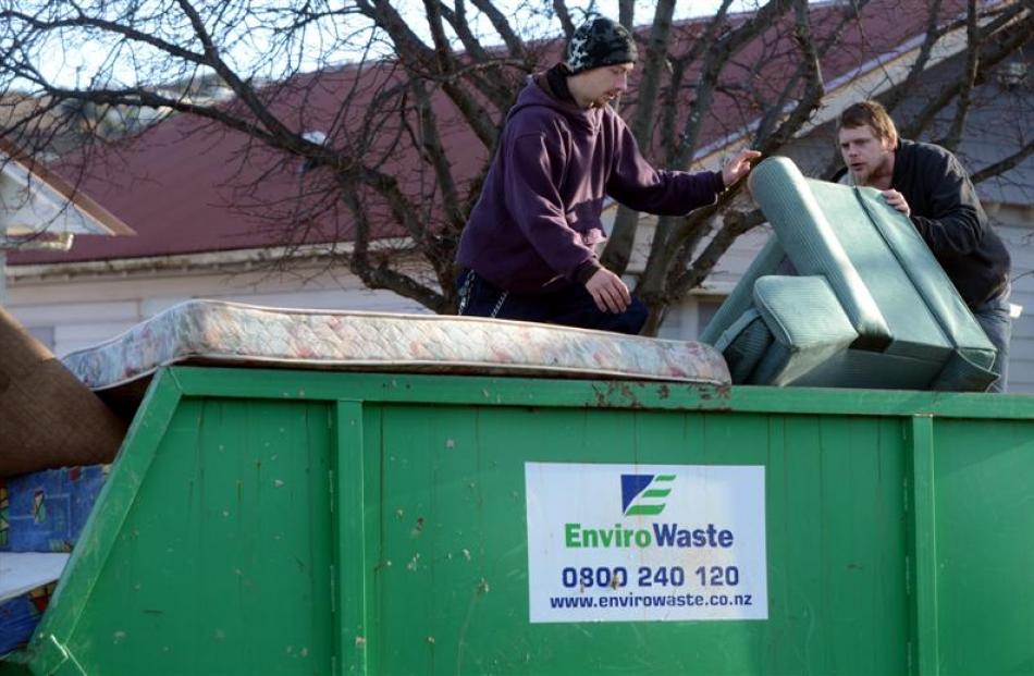 Mike Numm (left) and Mat Todd put  flood-damaged items  in the DCC skip in Surrey St.