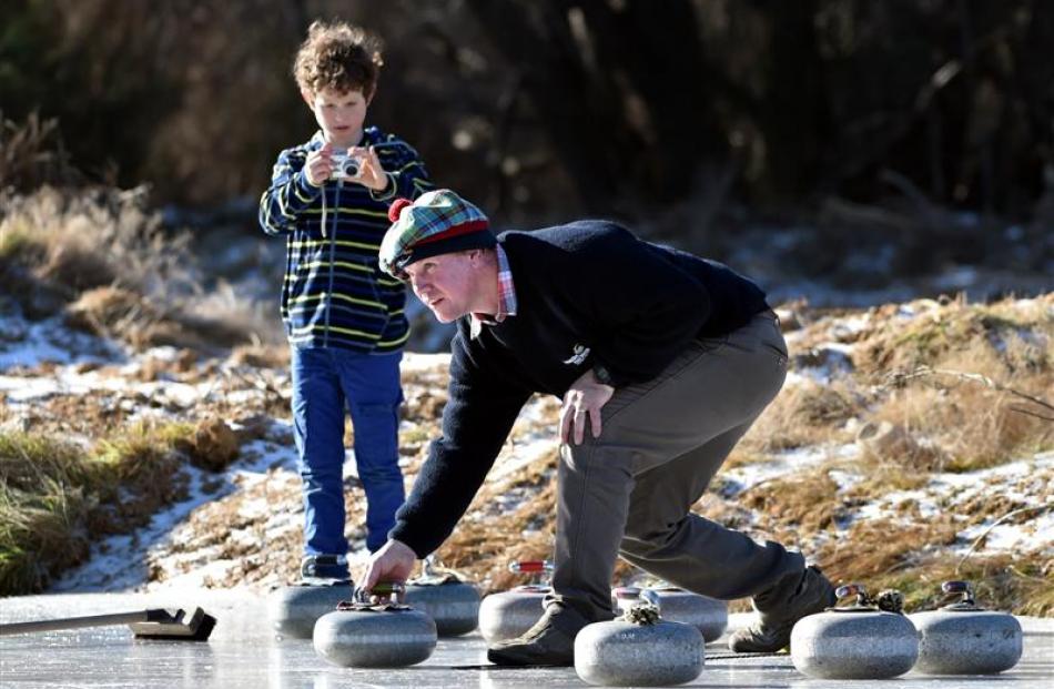 Sam Inder, of Naseby delivers his stone, while Sam Elkin (9), of Wellington snaps an action shot.