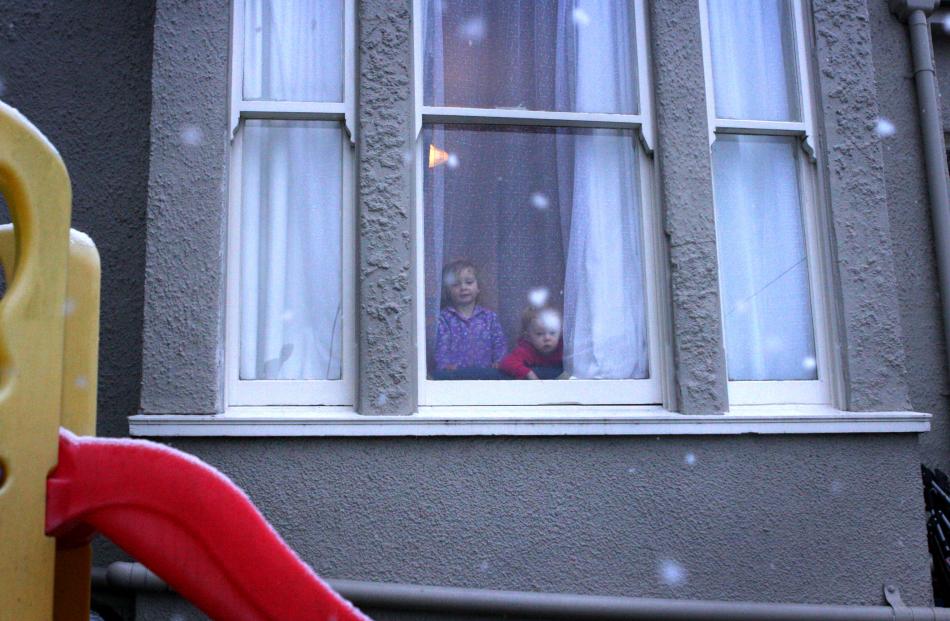 Ruby (2) and Meekah (1) Carline-Kirby look out their lounge window at the snow. Photo by...