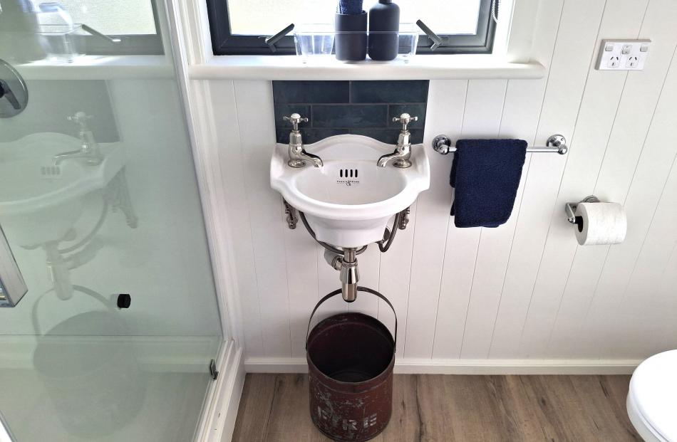 The bathroom includes a new, vintage-style basin and a backsplash of British racing green subway...