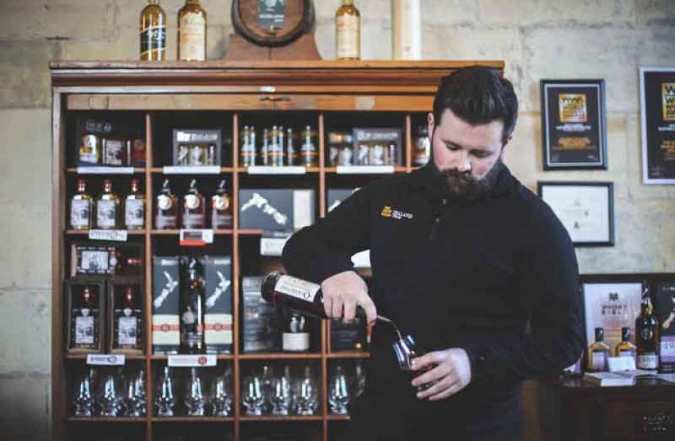 Duty manager Matthew Wicks pours a glass of whisky at the New Zealand Whisky Collection Cellar...