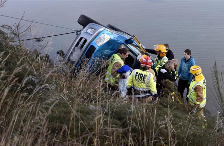 Emergency services attend to a car in Otago Harbour after it slid on ice near Blanket Bay.